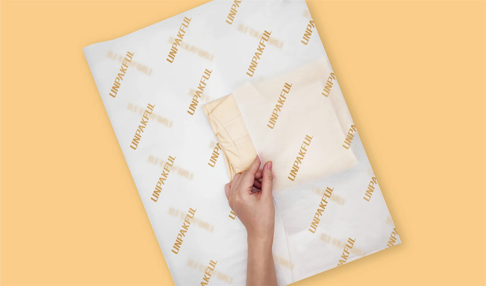 Hand arranging custom Unpakful tissue paper on a flat surface for packaging.