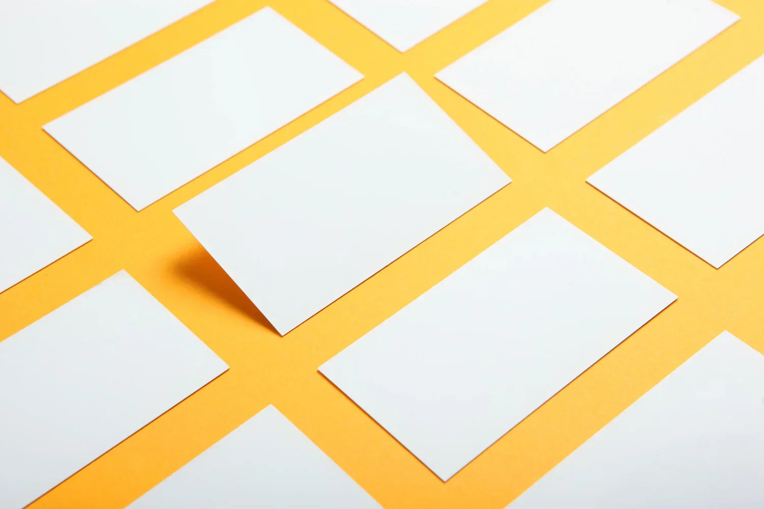 Assorted blank white paper sheets arranged on a bright yellow background, ideal for showcasing paper types.