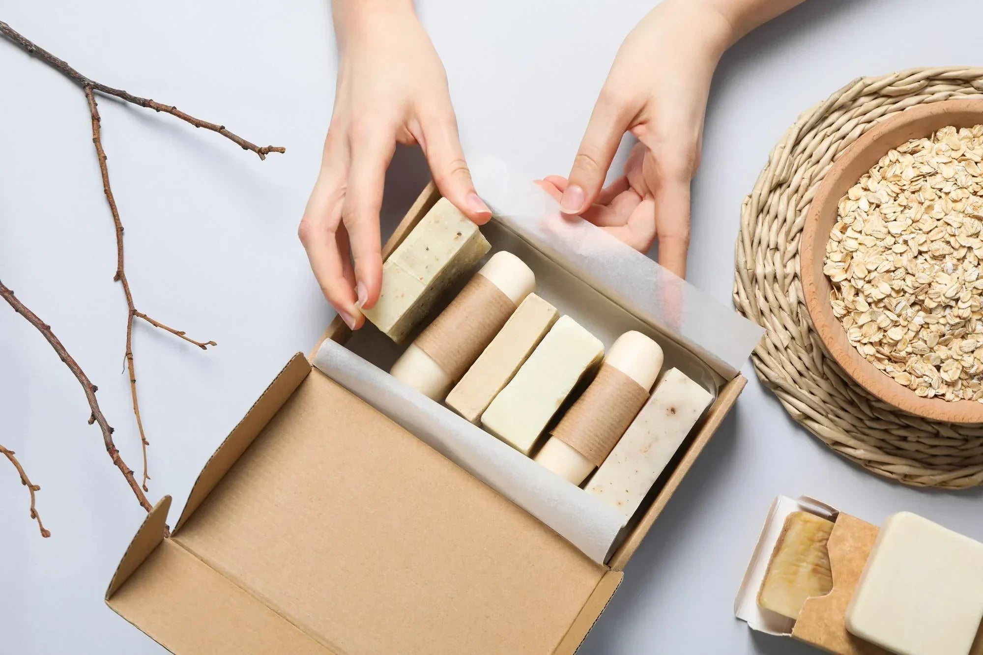 Person unboxing eco-friendly soap bars from a cardboard packaging box with natural ingredients nearby.