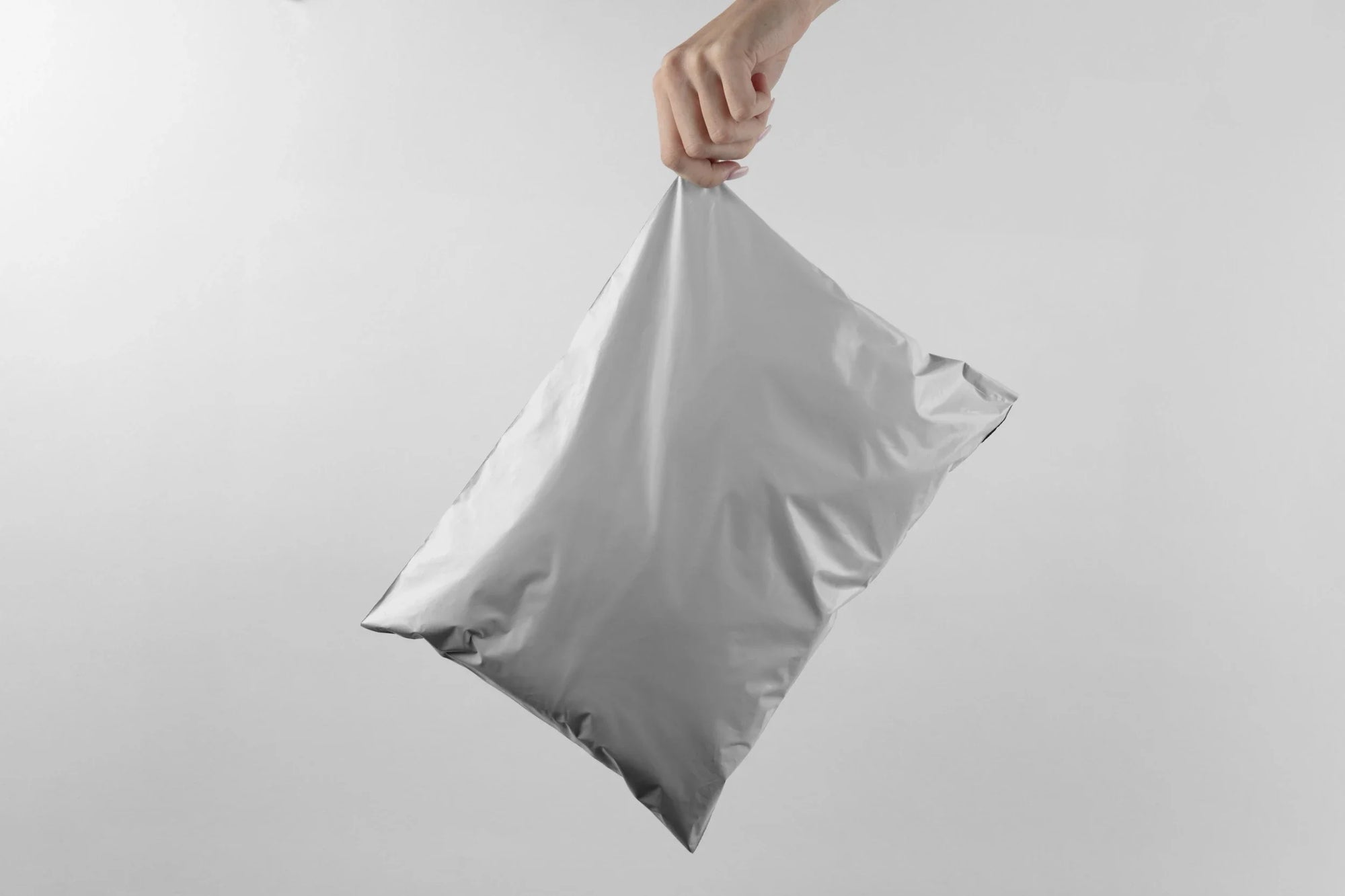 Person holding a silver polymailer bag, showcasing efficient packaging for e-commerce businesses.
