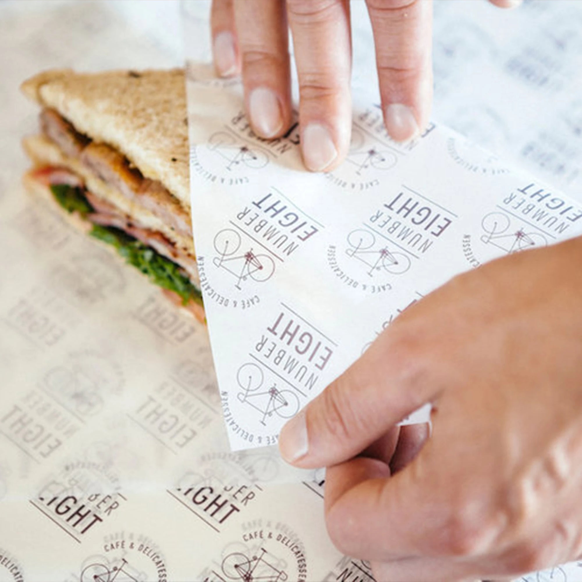 Custom food paper being used to wrap a sandwich, showcasing branded print design and quality material.