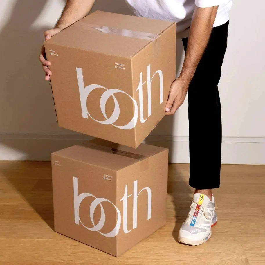 Person carrying two premium custom shipping boxes with stylish branding and durable design for secure product delivery.