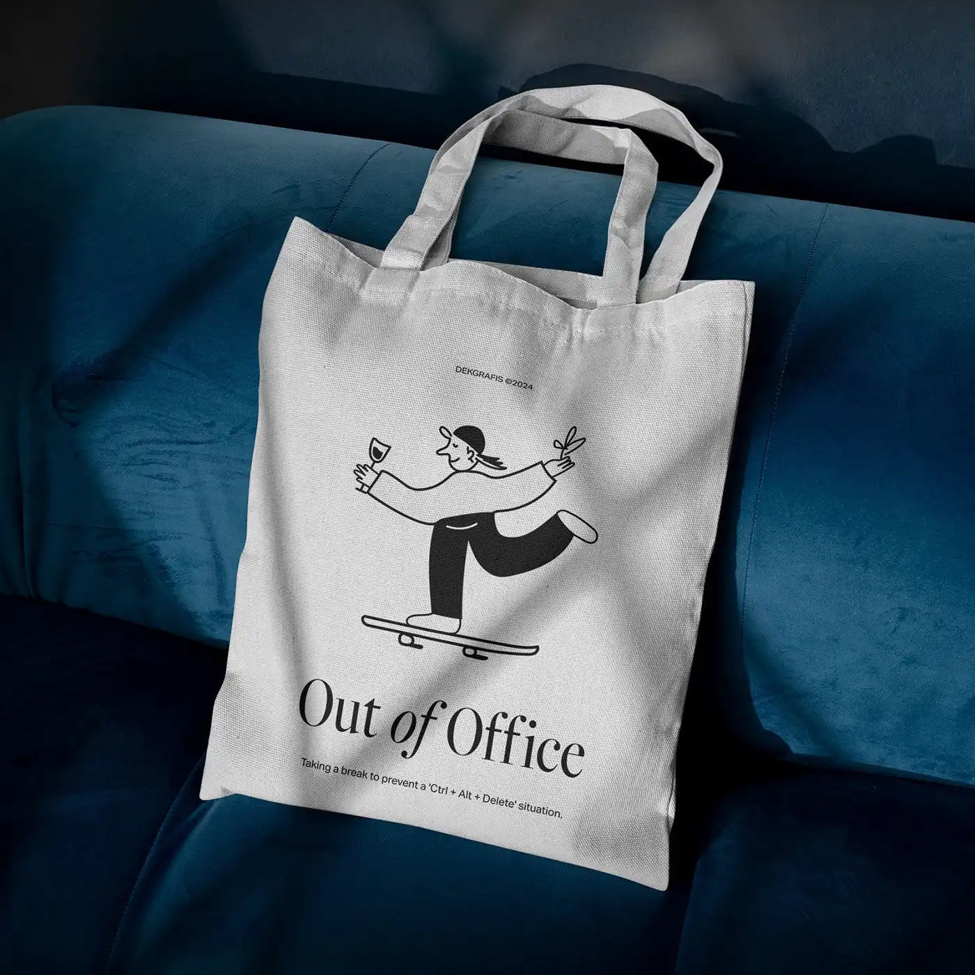 Custom tote bag with playful "Out of Office" design on a blue couch background.