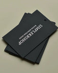 Stack of customizable black hang tags with stylish white lettering for product branding.