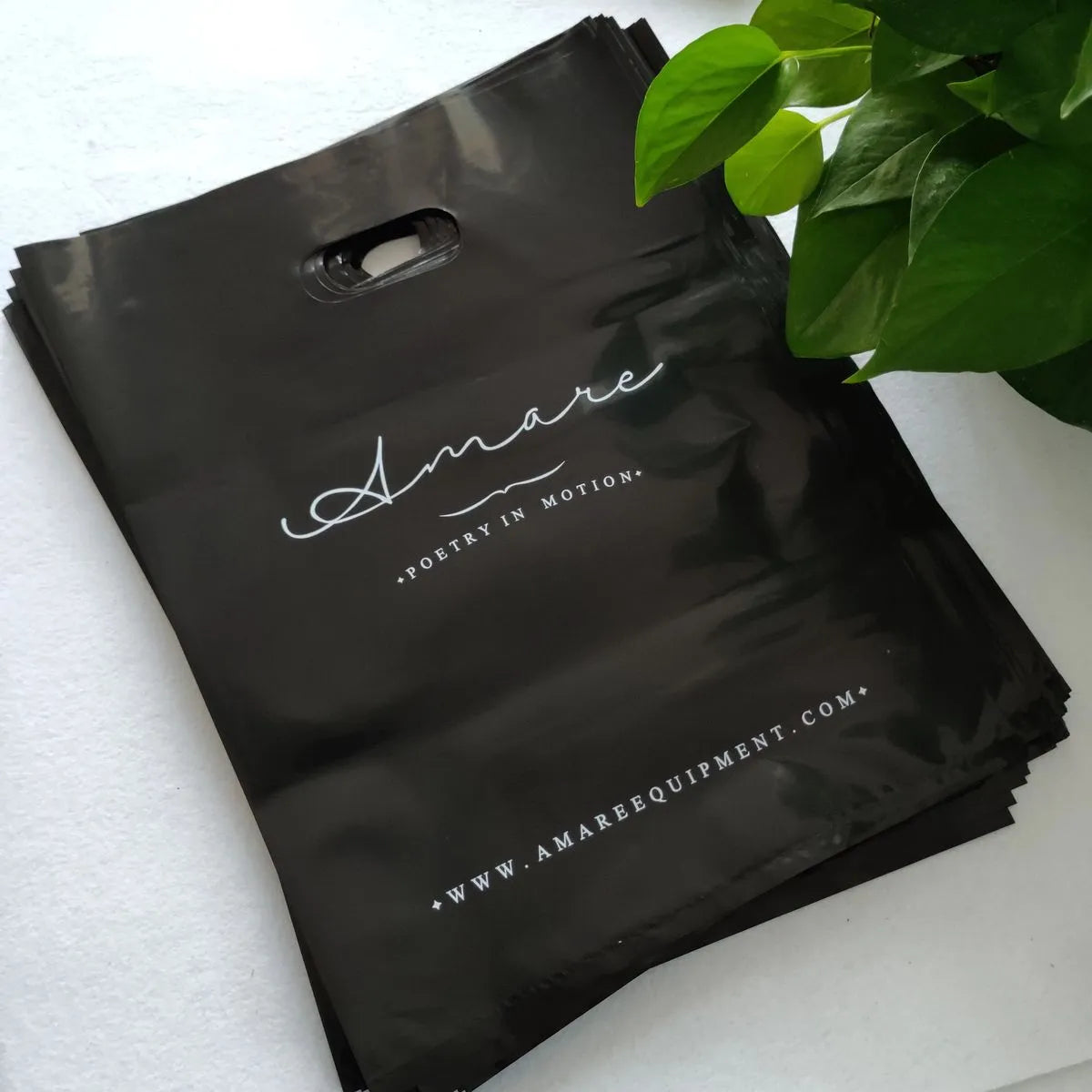Custom die cut handle bags in black featuring 'Amare' logo, ideal for brand promotions and stylish packaging.