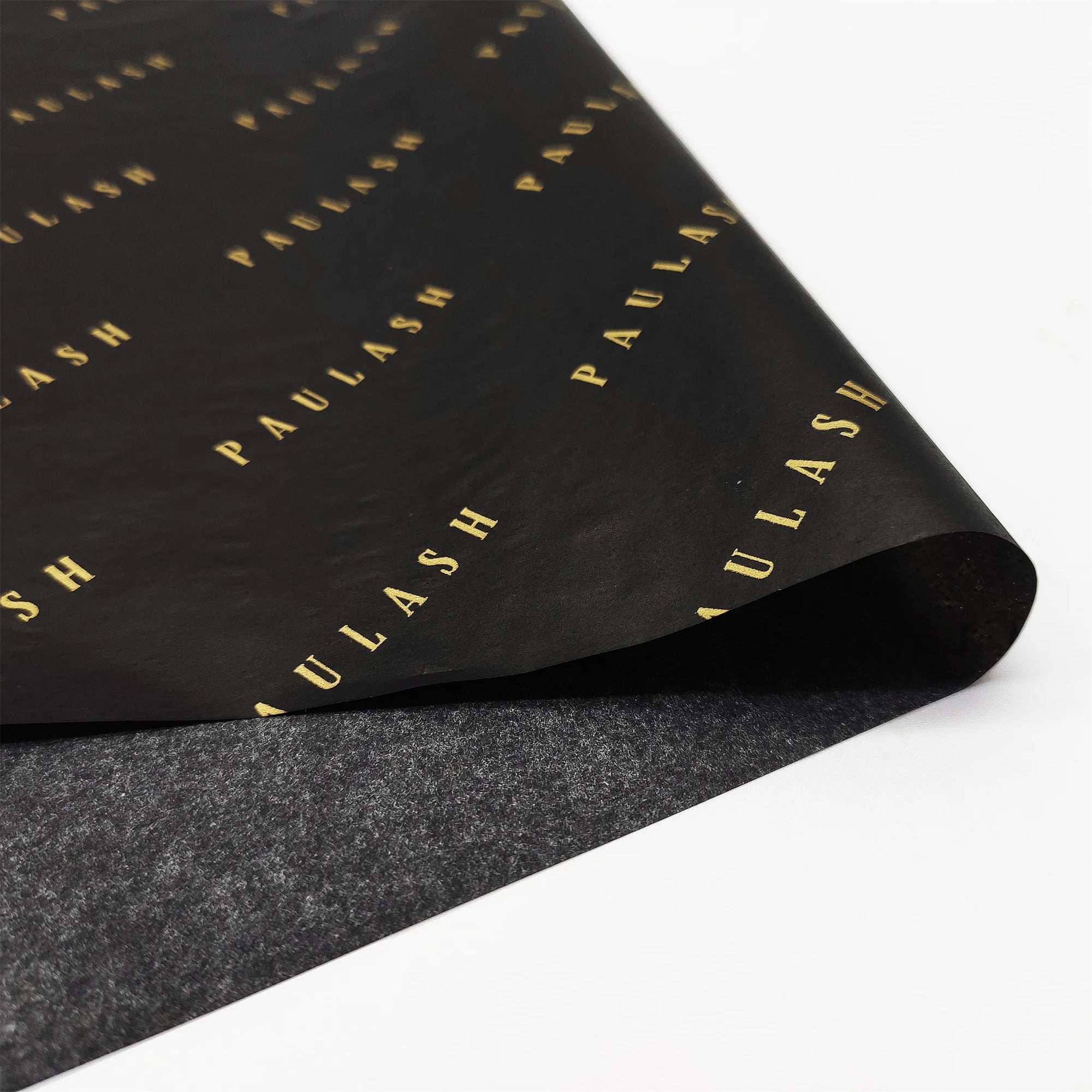 Custom tissue paper featuring black background with elegant gold "PAULASH" branding for sophisticated packaging solutions.