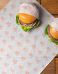Custom deli paper featuring logo-printed design, wrapping two delicious burgers on a rustic wooden table.