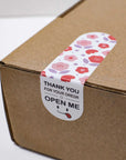 Custom floral sticker on a cardboard box with a "Thank You" message and an invitation to "Open Me".