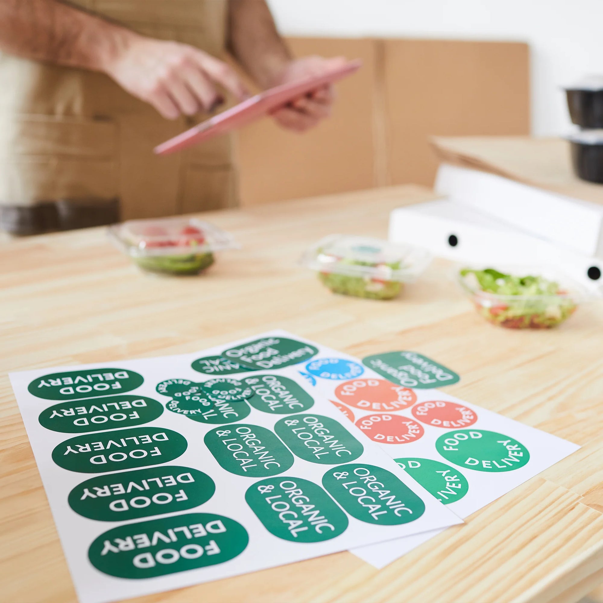 Custom die-cut stickers with various food delivery and organic labels placed on a wooden table.