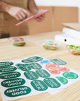 Custom die-cut stickers with various food delivery and organic labels placed on a wooden table.