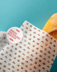 Bread wrapped in custom deli paper mockup with bakery pattern and logo on blue background.
