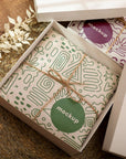 Custom round stickers displayed on gift wrap in a stylish box, showcasing branding and packaging design.