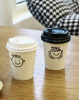 Custom Paper Cups with playful designs showcased on a wooden table, perfect for branding in coffee shops and cafés.