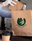 Custom paper bag with 'meow coffee' logo, held by barista, showcasing eco-friendly packaging.