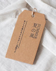 Custom hang tag with summer design, showcasing stylish branding and unique craftsmanship on a textured fabric background.