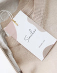 Custom hang tag on a sweater in a box, showcasing professional design and branding for a stylish presentation.