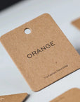 Custom hang tag in kraft paper with the word 'ORANGE' and tagline, ideal for product branding.