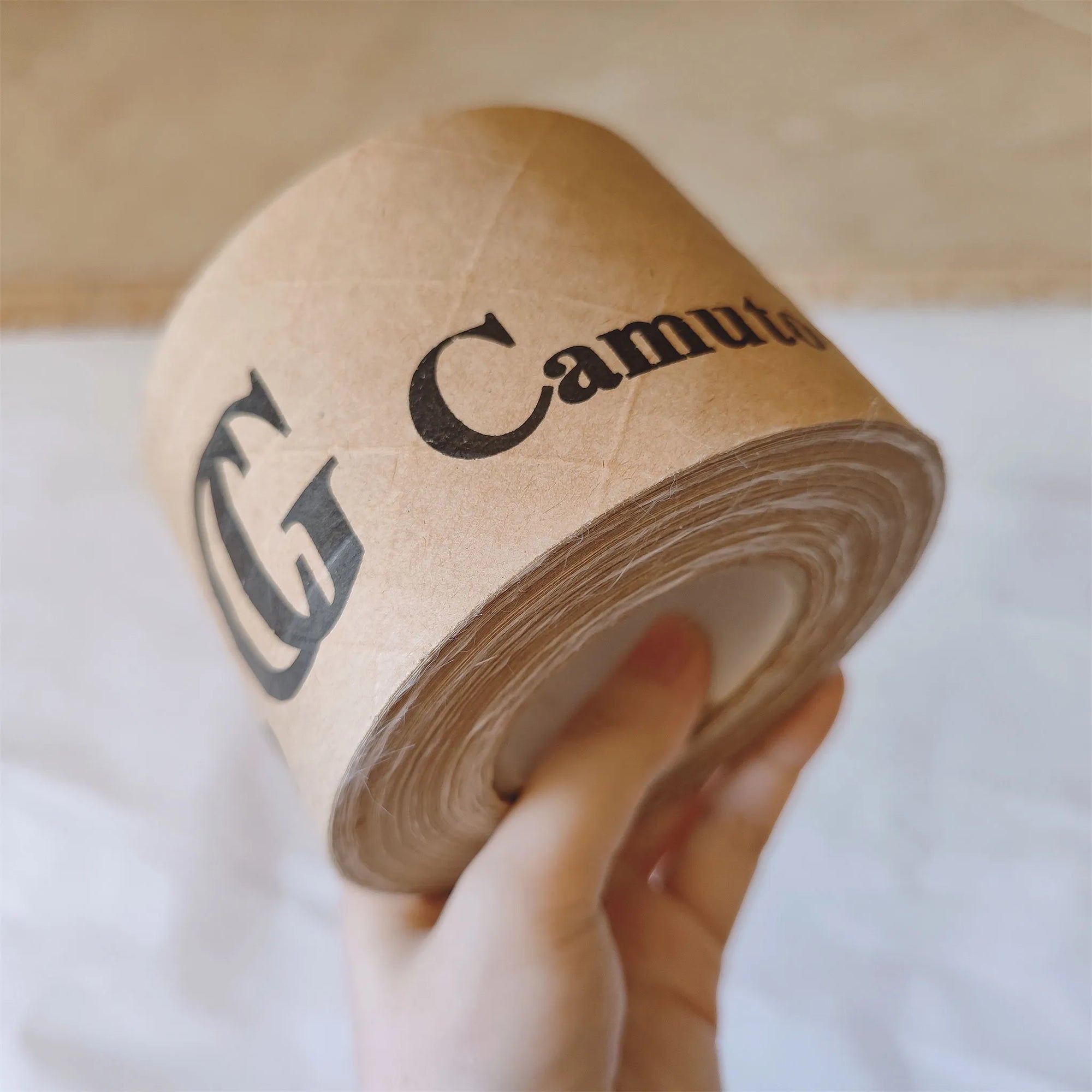Custom water-activated tape with branded design, held in hand for secure packaging solutions.