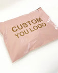 Custom pink poly mailer with "CUSTOM YOU LOGO" printed in gold for stylish shipping solutions.