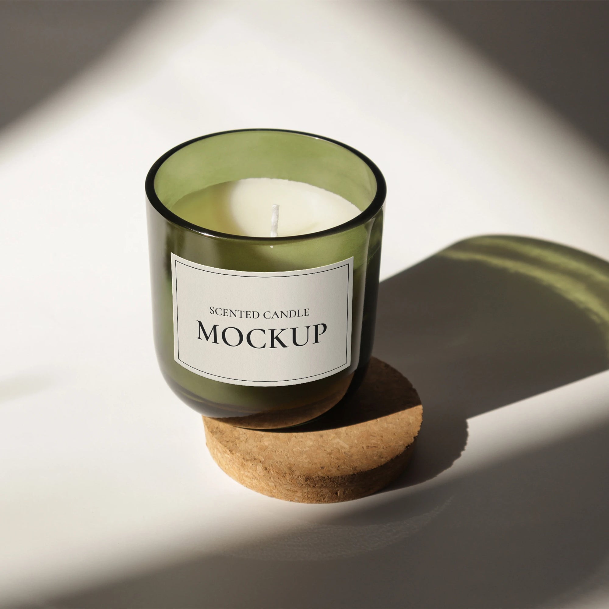 Mockup of a scented candle in a green glass jar on a cork coaster, showcasing a minimalist design.