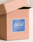 Custom square sticker mockup on a brown paper box, showcasing personalized design options for branding.