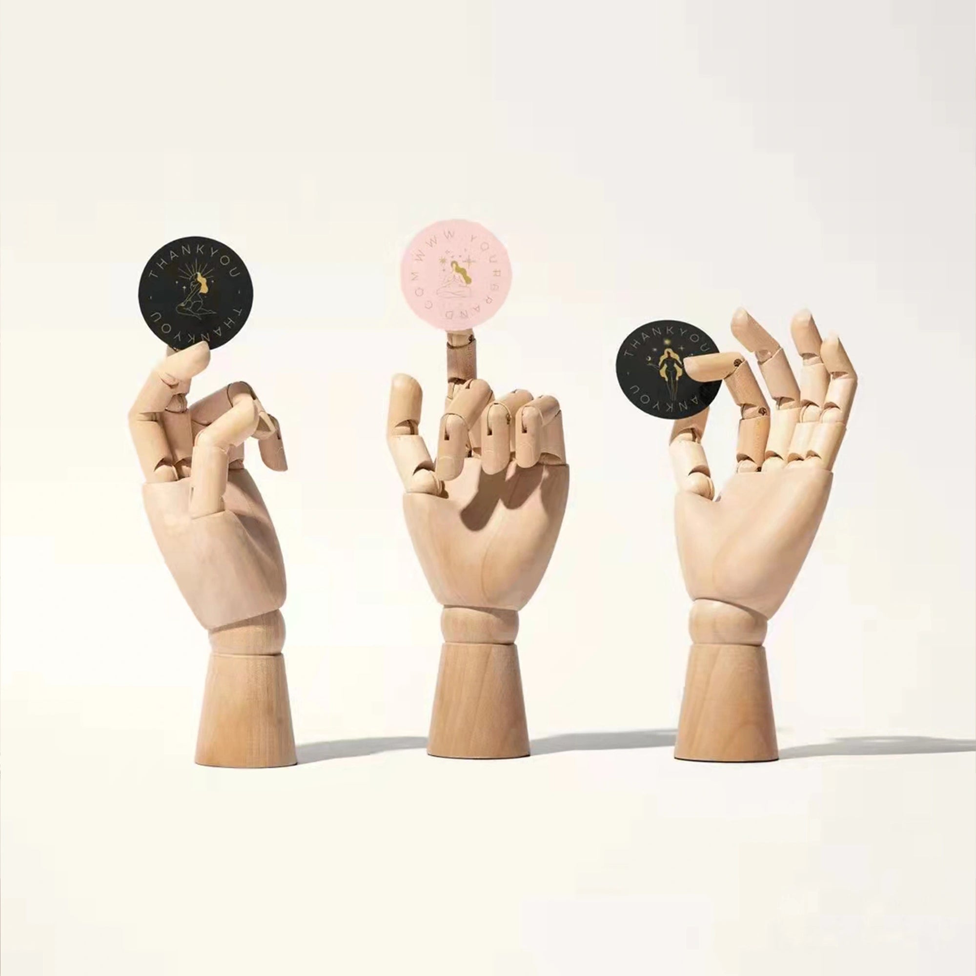 Custom round stickers showcased on wooden hands for branding and promotional use.