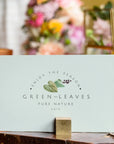Custom card with 'Enjoy the Season' design, featuring greenery and elegant branding in a floral setting.