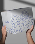 Custom shipping box with cheerful flower designs, held by hands, showcasing unique brand packaging.