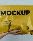 Mockup of a yellow custom poly mailer being held, showcasing eco-friendly packaging design for branding.