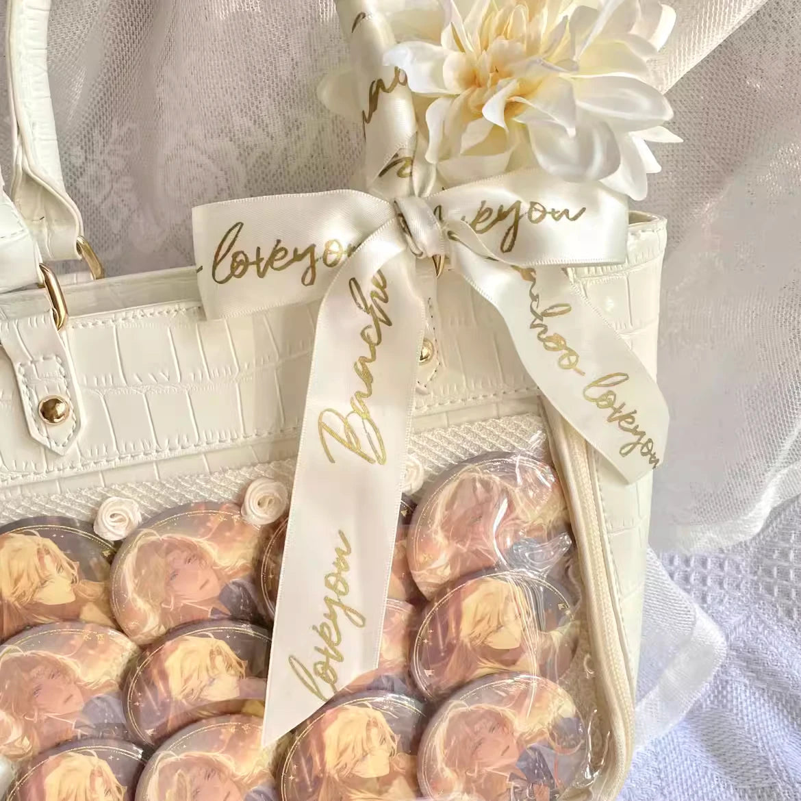 Custom satin ribbon with "love you" text decorates a stylish handbag next to luxury cookies and a flower.