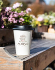 Custom Paper Cups featuring a logo on a coffee cup amidst flowers on a wooden surface.