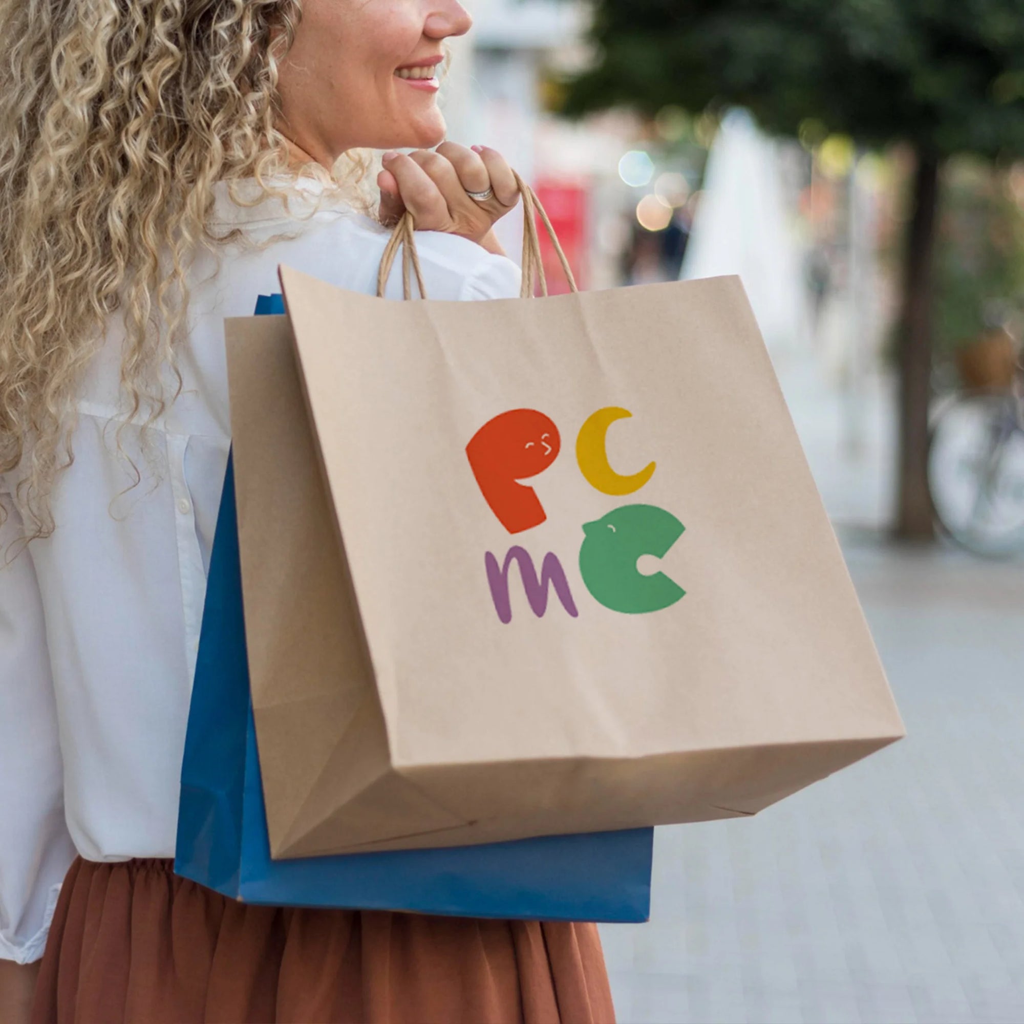 Woman holding custom paper bags with colorful logo, showcasing eco-friendly and stylish design for branding.