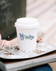 Custom Paper Cups featuring a logo on a coffee cup with a notebook and hands, perfect for branding and drink packaging.