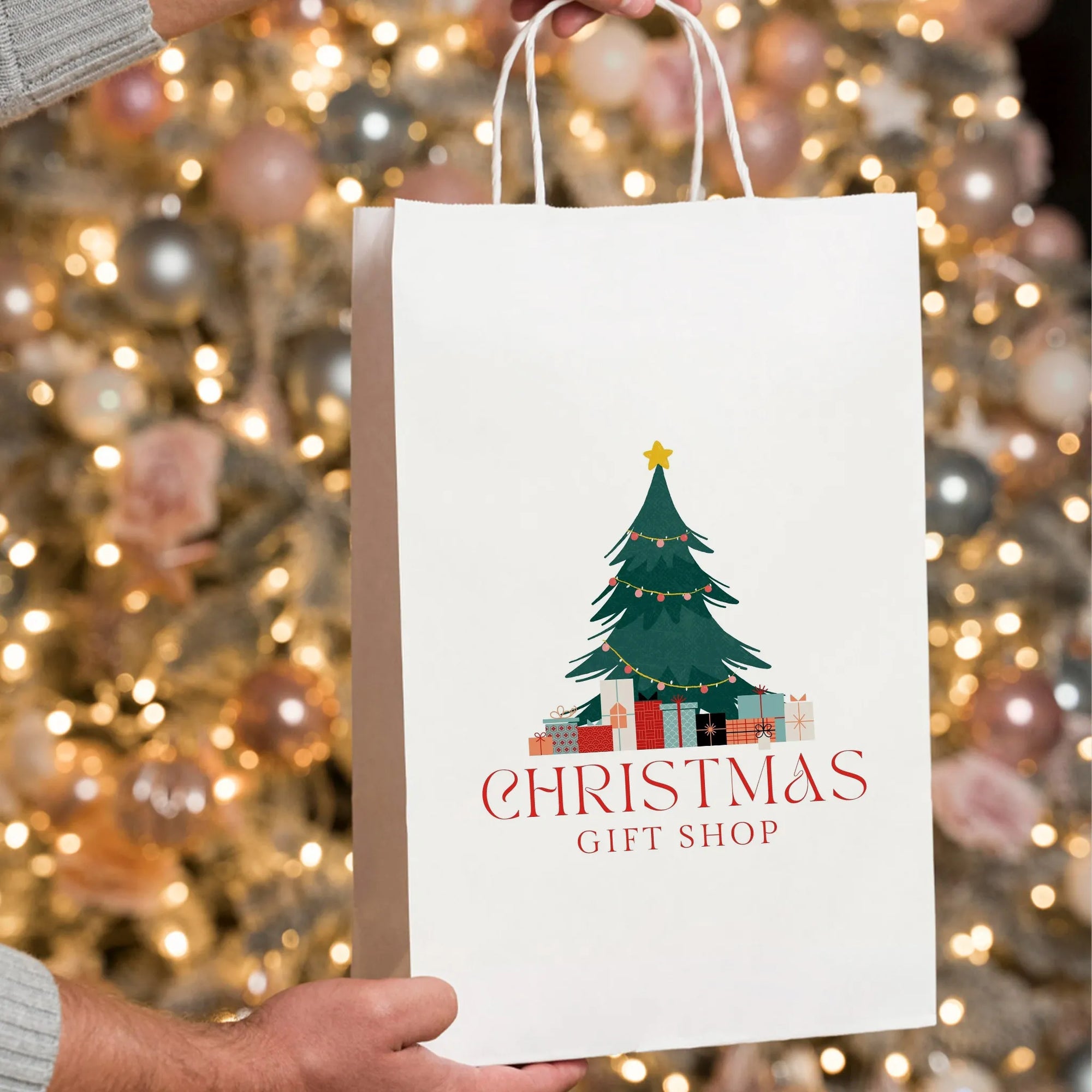 Custom white paper bag with Christmas tree design for gift shops, surrounded by festive holiday lights.