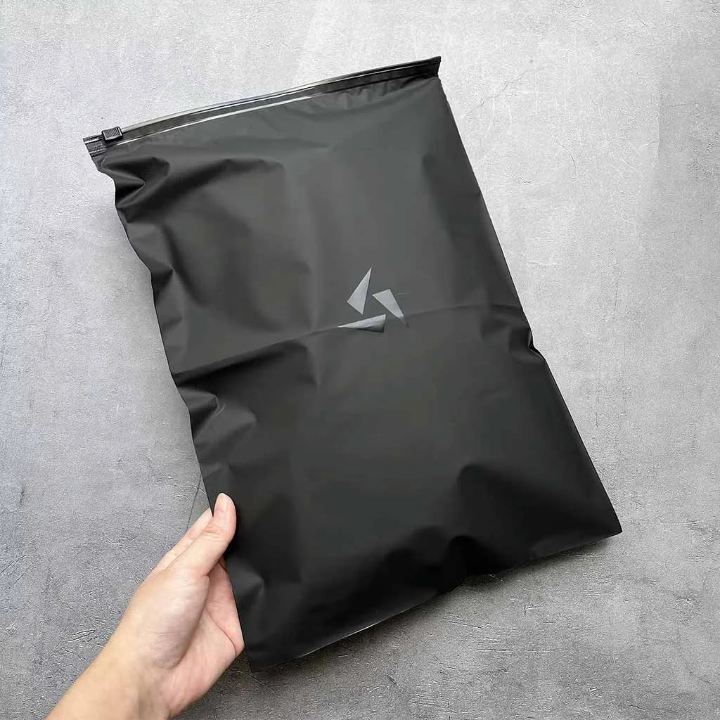 Hand holding a sleek custom black zipper bag with a matte finish, ideal for premium packaging solutions.