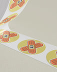 Custom round stickers with a band-aid design printed on a roll, perfect for branding and promotional use.