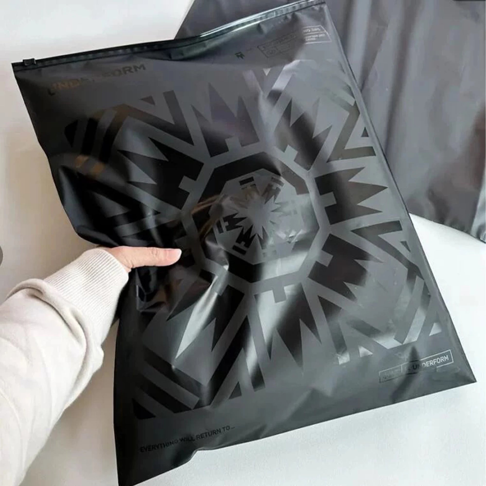 Person holding a sleek black zipper bag with a unique geometric design, ideal for stylish packaging.