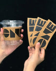 Custom Cup Sleeves featuring bold black design on takeout cups held by hands.