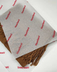 Custom tissue paper featuring brand name "Heartland" wrapping a brown scarf for elegant packaging.