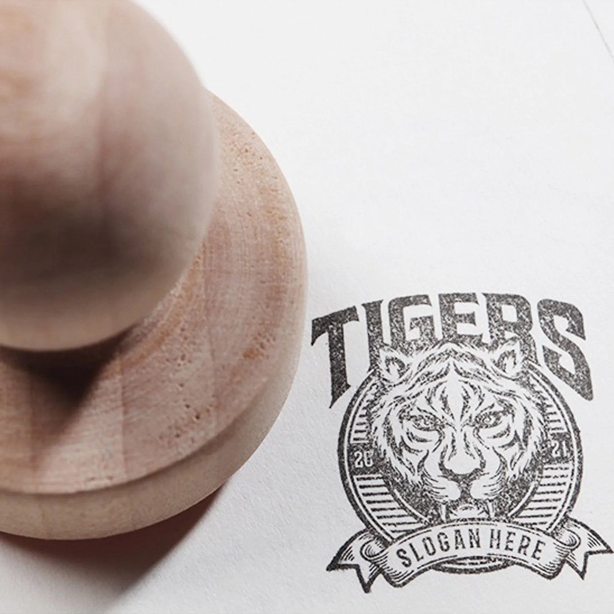 Custom rubber stamp imprints a tiger logo with the text "TIGERS" and "SLOGAN HERE" on paper.