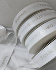 Custom satin ribbon rolls with embossed "TASOKO" logo, featuring a soft, luxurious finish. Perfect for gifts and decorations.