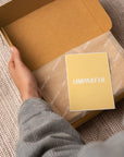 Person holding a custom branded card inside a stylish packaging box, showcasing a memorable unboxing experience.