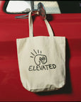 Custom tote bag with unique 'ELEVATED' design hanging on a red car door, showcasing style and sustainability.