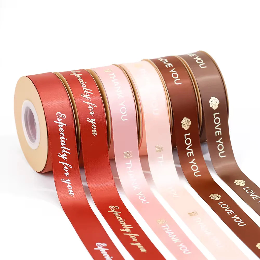 Custom ribbon rolls in various colors with printed messages, perfect for packaging and crafting projects.