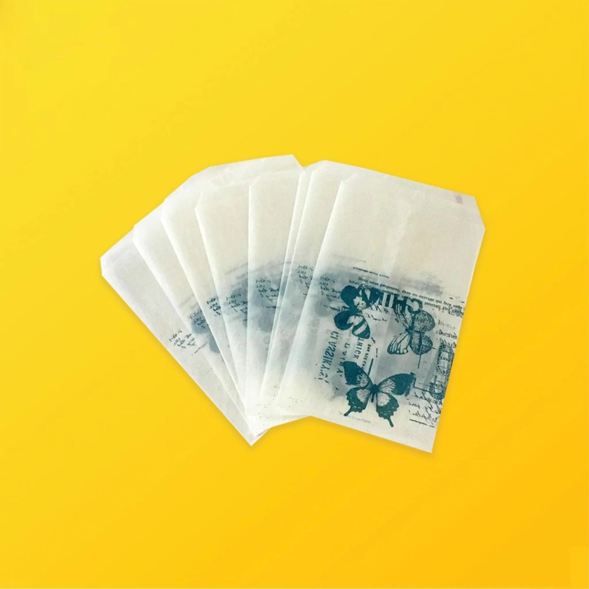 Custom glassine bags with butterfly prints on a yellow background, showcasing glossy finish and lightweight design.