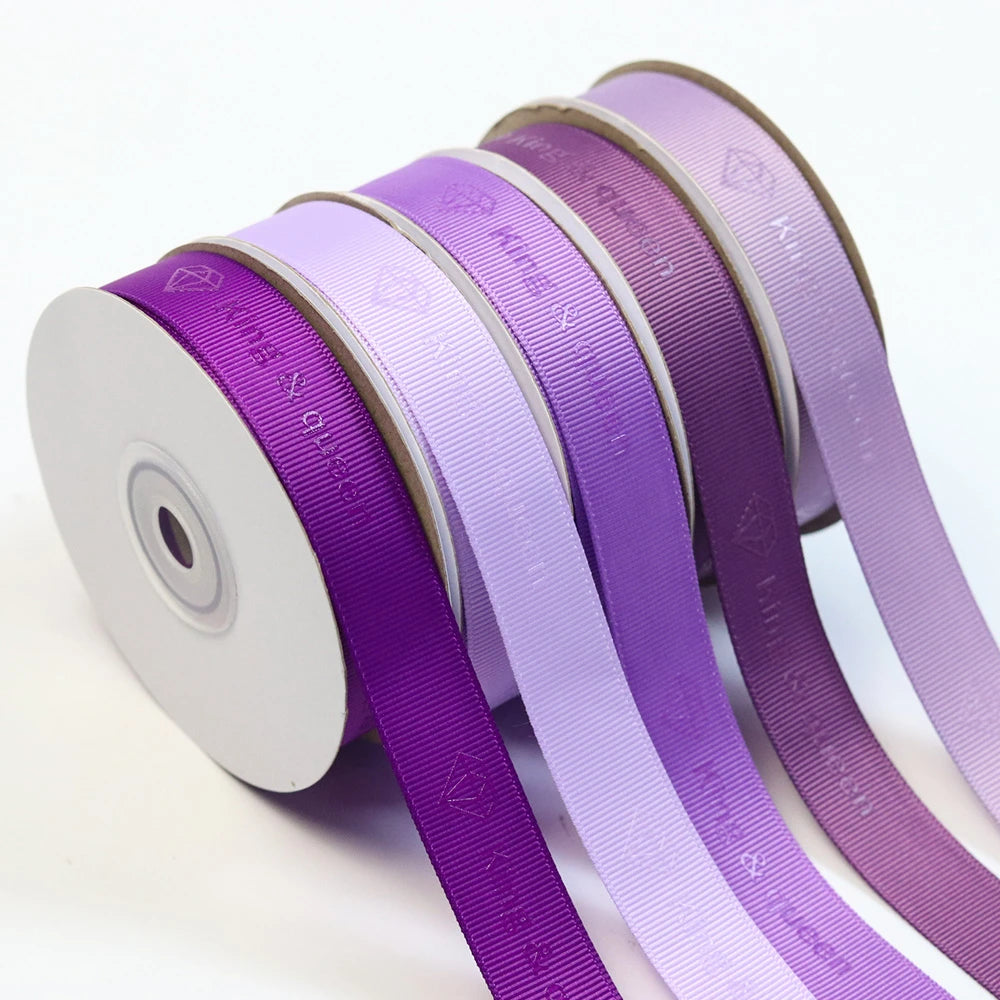 Custom grosgrain ribbon rolls in various shades of purple, showcasing distinctive ribbed texture for crafting and decoration.