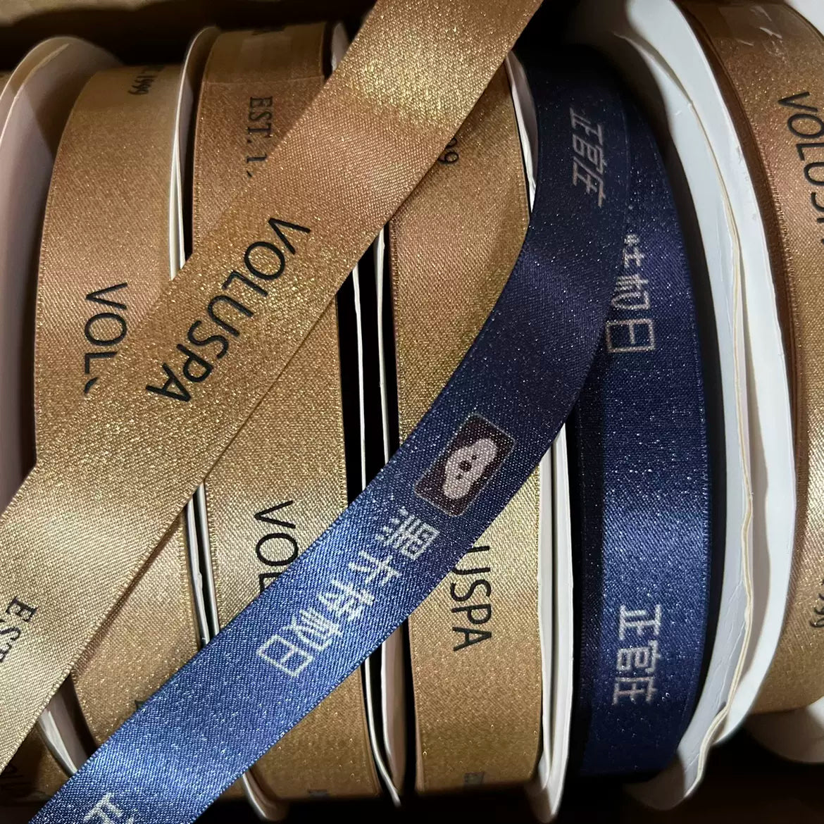 Custom metallic Lurex ribbons in gold and navy with printed designs, perfect for elegant packaging and décor.