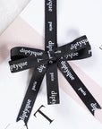 Custom black grosgrain ribbon with "diptyque" and "paris" text, elegantly tied around a gift package.