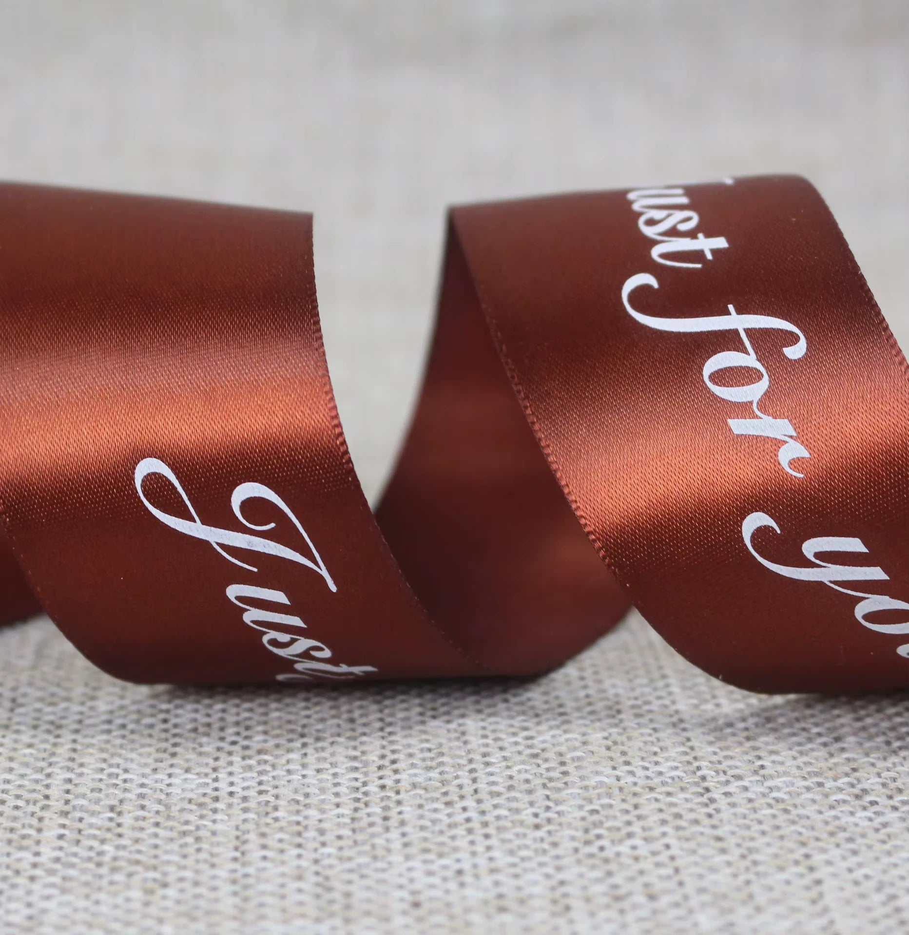 Custom satin ribbon in rich brown with "Just for you" message, perfect for elegant gift wrapping and decoration.