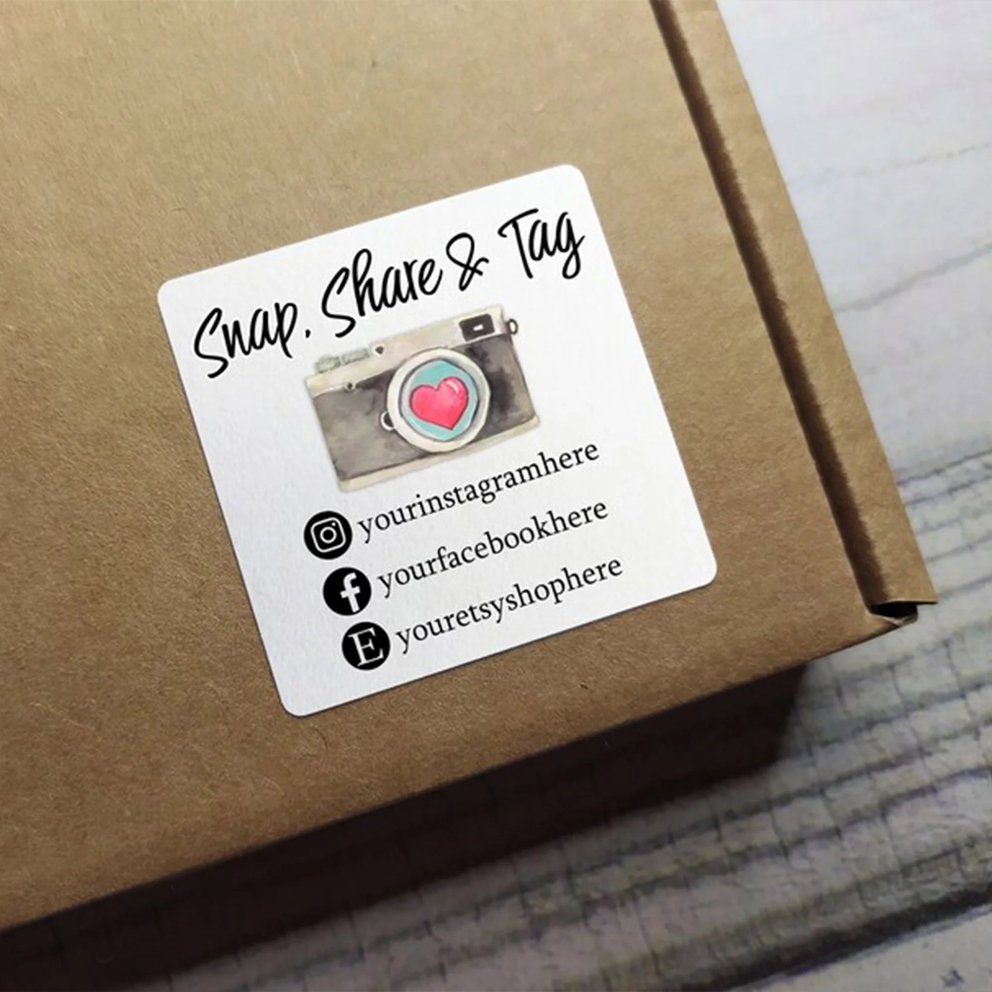 Custom square sticker on a package with social media handles and a camera graphic, inviting customers to engage.